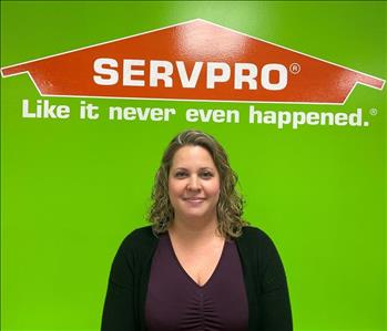 Kelli, office manager, pictured in front of SERVPRO logo