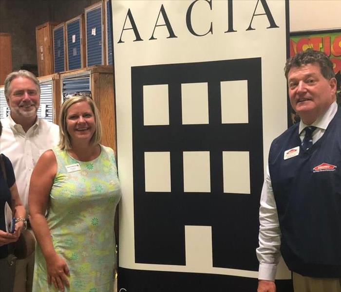 business professionals in front of AACIA sign