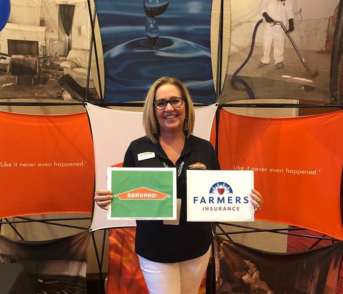 woman holding SERVPRO and Farmers Insurance signs